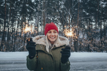 Lächelnde Frau mit Wunderkerzen im Winter - FSIF01877