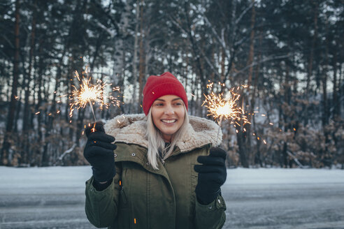 Smiling woman holding sparklers during winter - FSIF01877