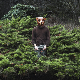 Mann mit Bärenmaske, der inmitten von Pflanzen steht - FSIF01881