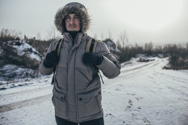 Nachdenklicher Wanderer, der seinen Rucksack trägt, während er in einer schneebedeckten Landschaft steht - FSIF01894