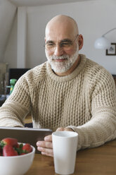 Älterer Mann benutzt digitales Tablet auf dem Tisch zu Hause - FSIF01900