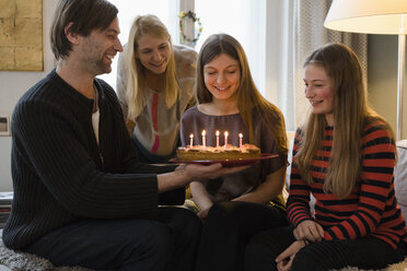 Glückliche Familie mit Geburtstagskuchen zu Hause - FSIF01922