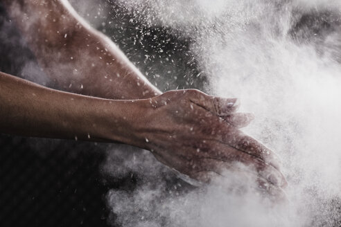 Beschnittenes Bild einer Frauenhand, die Kreidepulver für den Sport abstreut - FSIF01940