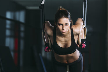 Front view of woman hanging on gymnastic rings at gym - FSIF01944