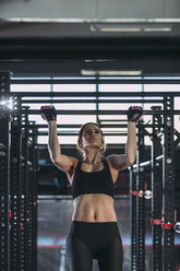 Front view of female athlete doing chin-ups at gym - FSIF01949