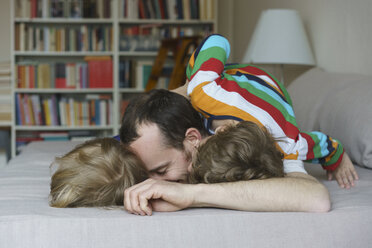 Glücklicher Vater mit fröhlichen Kindern zu Hause auf dem Bett liegend - FSIF01964