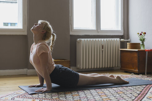 Seitenansicht einer jungen Frau, die zu Hause Yoga macht - FSIF01970