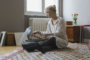 Full length of woman playing record while sitting at home - FSIF01974