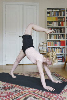 Junge Frau macht Yoga im Wohnzimmer zu Hause - FSIF01976