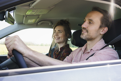 Glücklicher Mann am Steuer, der neben einer Frau im Auto sitzt, lizenzfreies Stockfoto