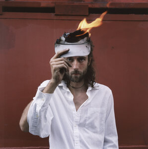 Ein Mann mit weißem Hemd hält ein brennendes Stück Papier - FSIF01984