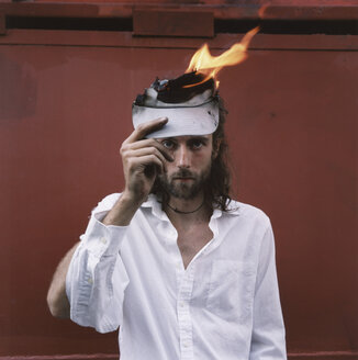 A man with a white shirt holding a piece of paper on fire - FSIF01984