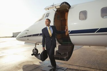 Geschäftsmann beim Einsteigen in ein Privatflugzeug - FSIF02048
