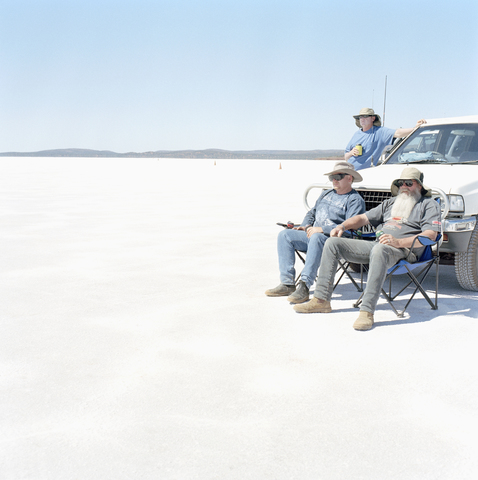 Drei Männer und ein Auto in einer Wüste, lizenzfreies Stockfoto