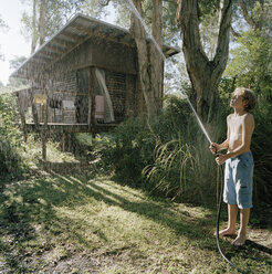 A boy spraying water near a forest hut - FSIF02059