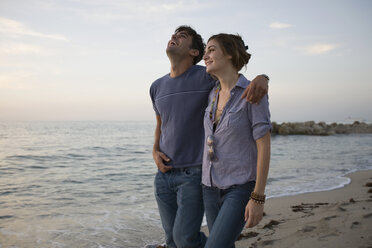 Couple walking along beach together and laughing - FSIF02078
