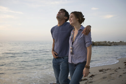 Paar spaziert zusammen am Strand entlang und lacht - FSIF02078