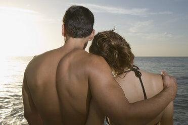 Couple embracing on beach at sunset - FSIF02086