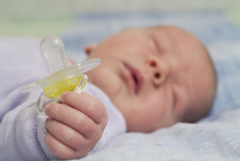 Neugeborenes Baby schläft und hält Schnuller - FSIF02121