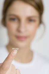 Eine Frau hält eine Kontaktlinse am Finger - FSIF02138