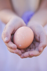 Junges Mädchen hält Ei in den Händen - FSIF02145