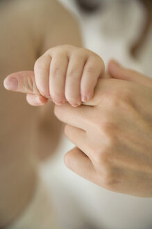 Baby greift nach dem Finger der Mutter - FSIF02150