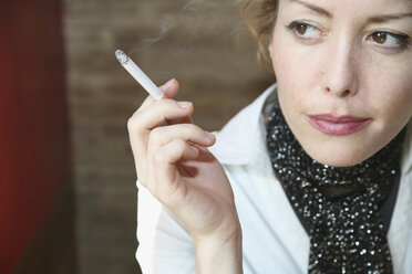 Woman sitting in cafe smoking a cigarette - FSIF02153