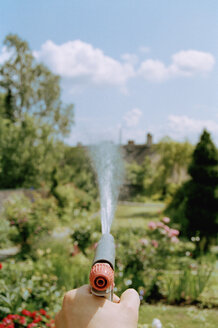 Mann bewässert Blumen mit Schlauch - FSIF02155