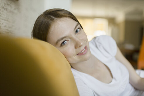 Portrait of smiling woman resting on sofa at home - FSIF02171