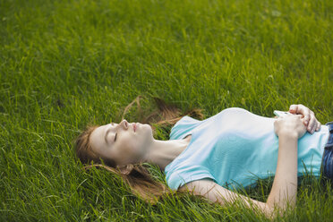 Junge Frau ruht mit geschlossenen Augen auf einer Wiese - FSIF02174