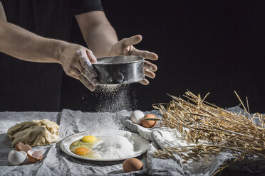 Midsection of man sprinkling flour over eggs at table - FSIF02177