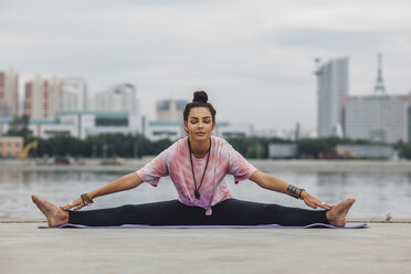 Schöne Frau übt Yoga gegen den Fluss in der Stadt - FSIF02182