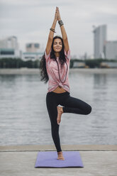 Schöne Frau übt Yoga in Tree Pose gegen Fluss - FSIF02184