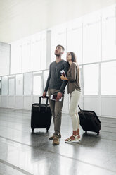 Full length of young couple with luggage and boarding passes at airport - FSIF02213