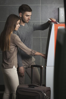 Junges Paar benutzt einen Geldautomaten am Flughafen - FSIF02214