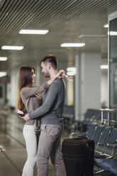 Seitenansicht eines romantischen jungen Paares, das sich am Flughafen umarmt - FSIF02226