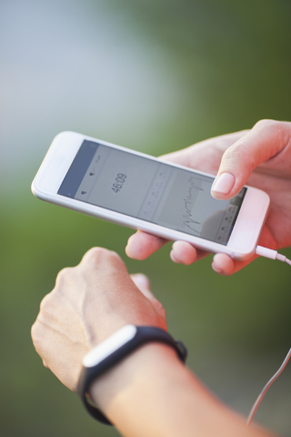 Ausgeschnittenes Bild einer Frau mit Schrittzähler und Mobiltelefon, lizenzfreies Stockfoto