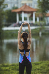 Rückansicht einer Frau beim Stretching im Park - FSIF02236