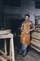 Porträt eines Zimmermanns vor einem Holzstapel in einer Werkstatt - FSIF02243