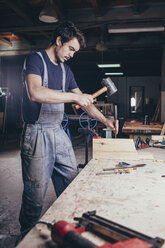 Zimmermann bei der Bearbeitung von Holz mit Hammer und Meißel in der Werkstatt - FSIF02245