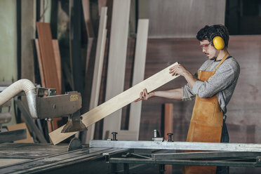 Tischler bei der Prüfung eines Holzstücks mit der Tischsäge in der Werkstatt - FSIF02255