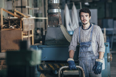 Portrait of carpenter standing by machinery at workshop - FSIF02256