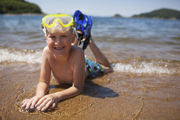 Porträt eines Jungen mit Schnorchel und Schwimmbrille am Strand liegend - FSIF02265