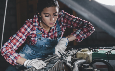 Mechanikerin repariert Automotor in der Werkstatt, lizenzfreies Stockfoto