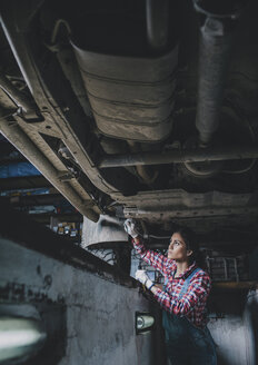 Female mechanic working underneath car at workshop - FSIF02269