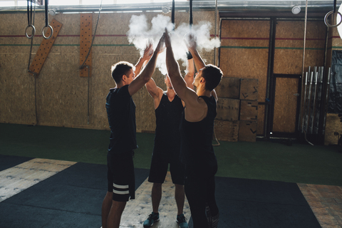 Entschlossene Sportler, die gemeinsam im Fitnessstudio Sportkreide abstauben, lizenzfreies Stockfoto