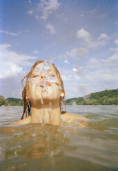 A young woman spitting water from a lake - FSIF02361