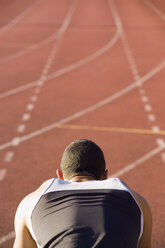 Rear view of a male athlete in starting blocks on a running track - FSIF02367