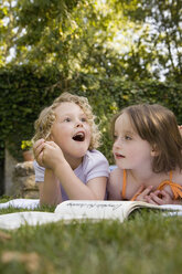 Two girls lying down side by side in a backyard - FSIF02370