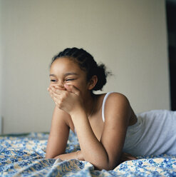 Girl lying on her bed laughing - FSIF02390